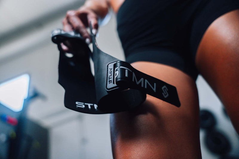 Atleta mostra la coppia di paracalli Hybrid STMN Fitness con logo in evidenza prima dell'allenamento